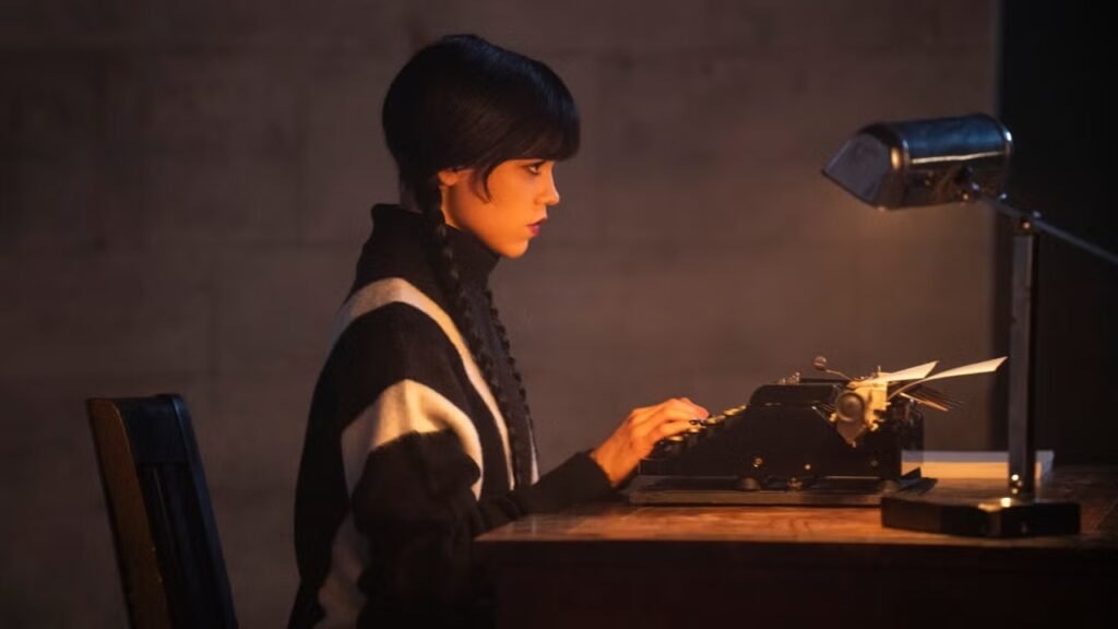 Jenna Ortega como Wandinha Addams sentada diante de uma máquina de escrever antiga