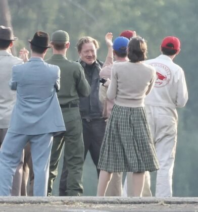 Brendan Fraser caracterizado conversa com figurantes e equipe em cena de corrida