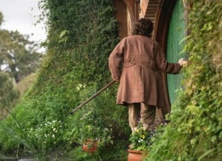 Frodo de costas diante da porta redonda de Bolsão em cena de The Hunt for Gollum