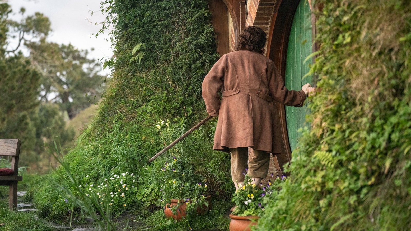 Frodo de costas diante da porta redonda de Bolsão em cena de The Hunt for Gollum