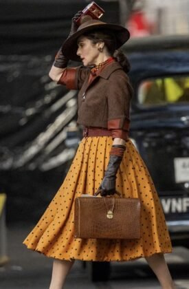 Rachel Weisz segura chap&eacute;u e maleta diante de um carro antigo