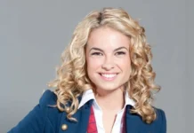 Retrato da atriz e cantora Lua Blanco sorrindo, de blazer azul e gravata vermelha