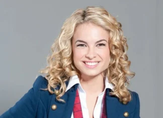 Retrato da atriz e cantora Lua Blanco sorrindo, de blazer azul e gravata vermelha